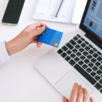 Une personne effectuant un achat en ligne avec une carte de crédit sur un ordinateur portable, présentant la technologie moderne du commerce électronique.