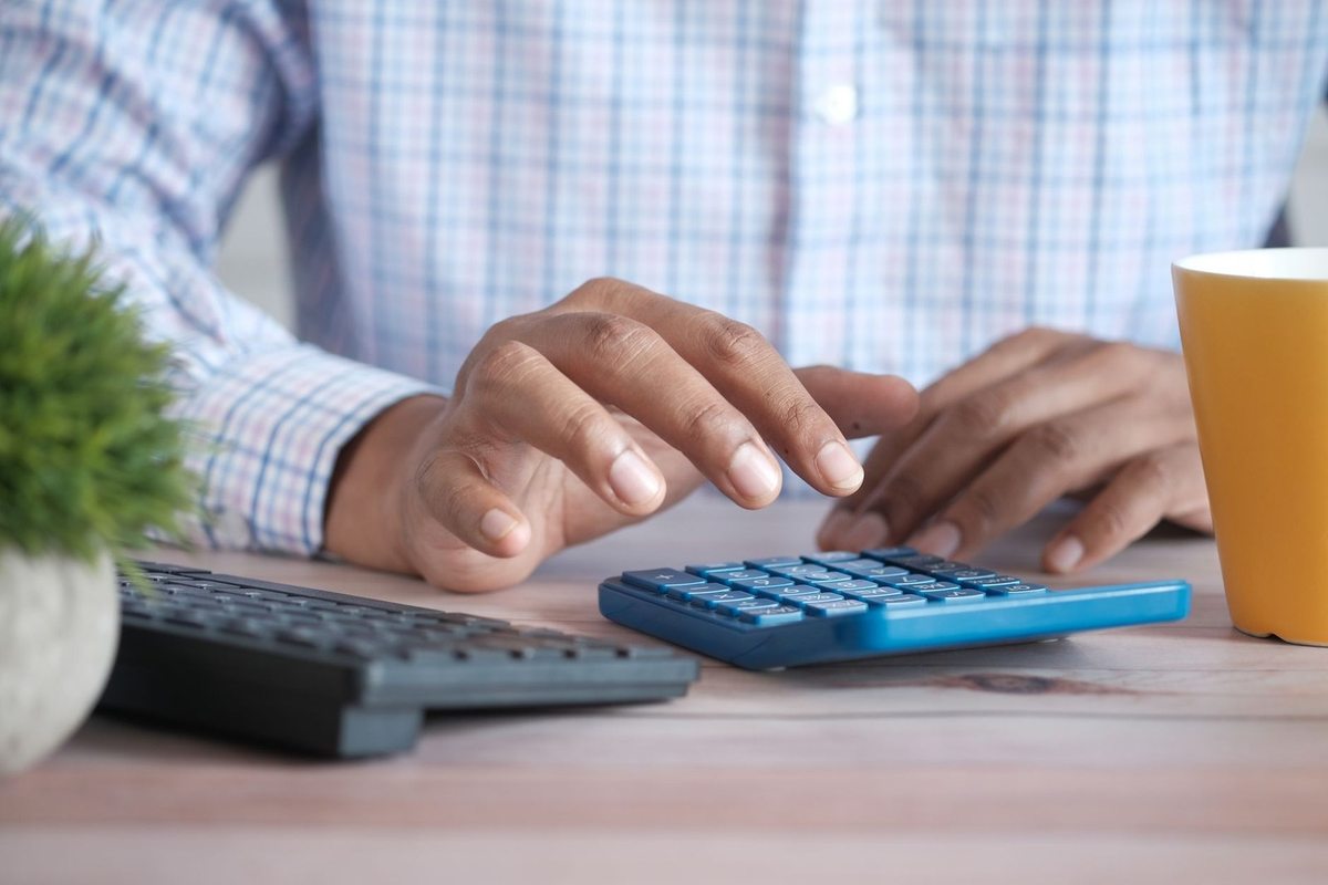 Personnes mains au clavier et à la calculatrice sur un bureau avec tasse et plante Personnes mains au clavier et à la calculatrice sur un bureau avec tasse et plante