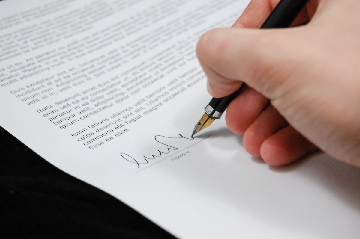 main écrivant sur un document avec un stylo noir main écrivant sur un document avec un stylo noir