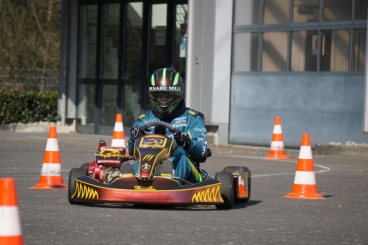 Un conducteur en kart traverse un circuit marqué par des cônes orange
