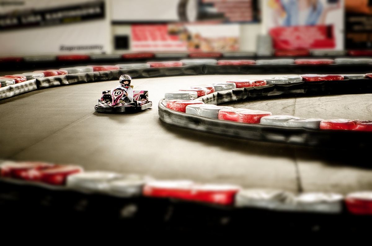 Un conducteur pilote un kart sur un virage de circuit intérieur Un conducteur pilote un kart sur un virage de circuit intérieur