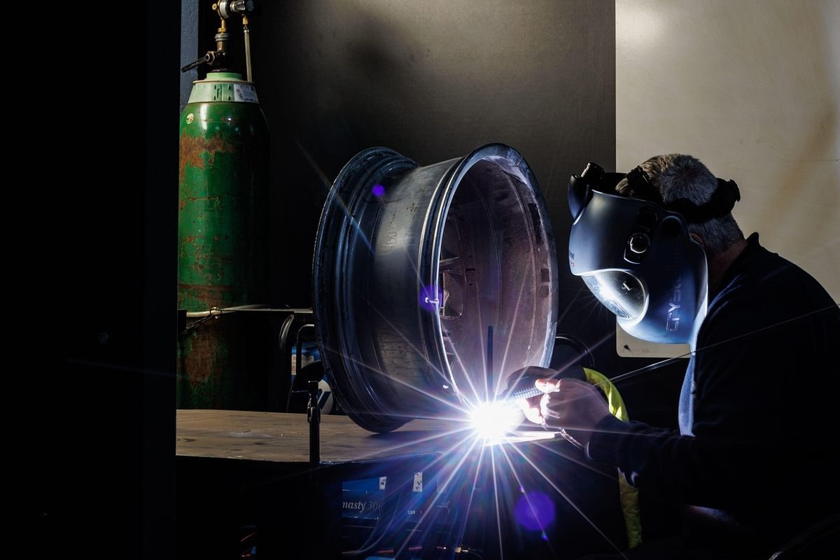 Un soudeur portant un casque protège un disque métallique en atelier Un soudeur portant un casque protège un disque métallique en atelier
