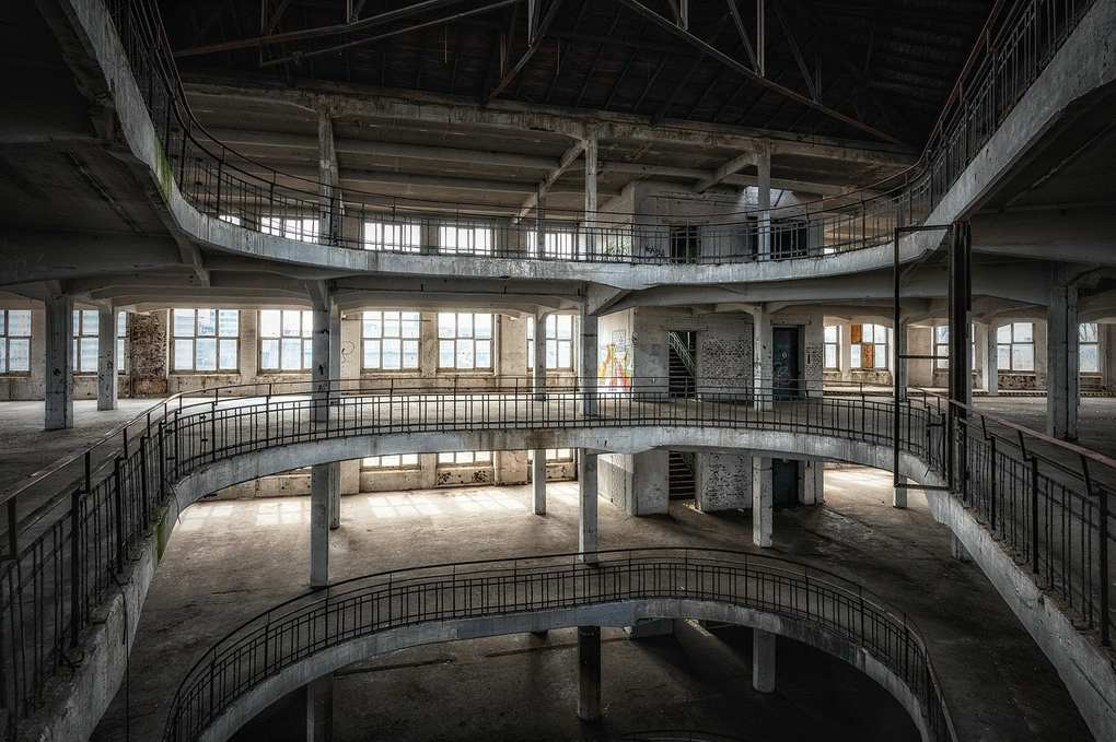 Bâtiment industriel à trois niveaux avec escaliers en spirale et fenêtres hautes